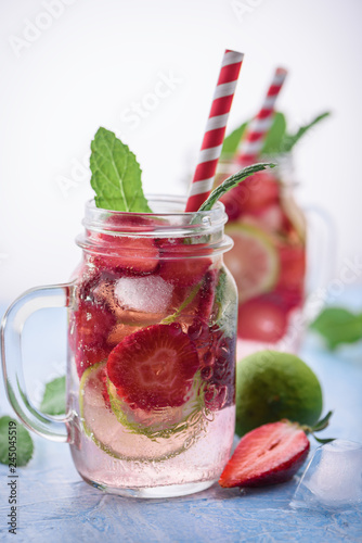 Close up view on lime and strawberry detox drink in glass mason jars on a blue background 7 photo