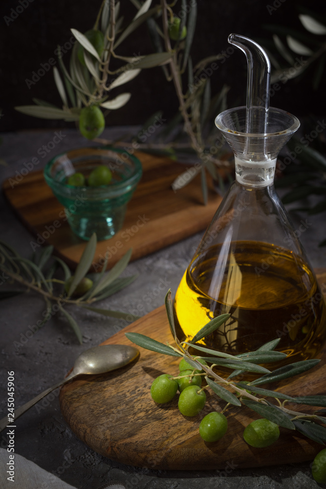 Extra virgin olive oil in glass bottle with branch of olives on rustic background. low key Extra virgin olive oil in glass bottle with branch of olives on rustic background. low key
