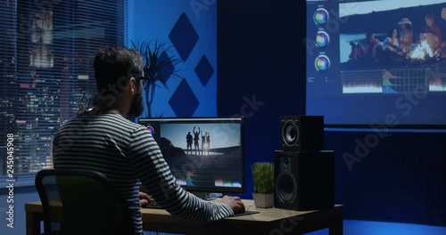 Medium shot of young man sitting back and editing video inside a room