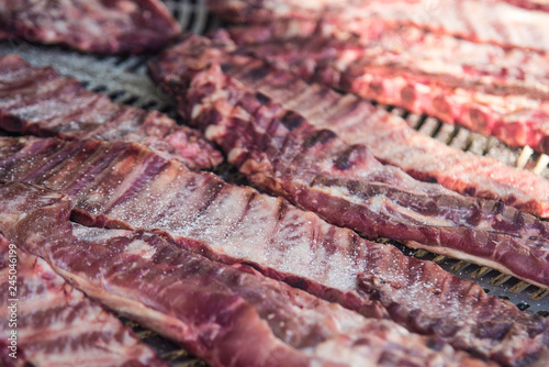 Fresh raw meat ribs with salt and pepper on big metal grill. Selective focus.3