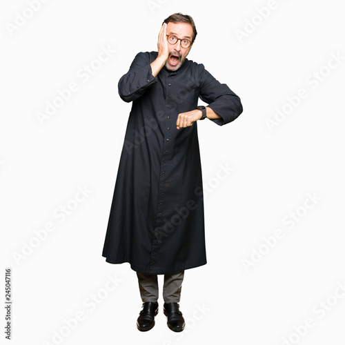 Middle age priest man wearing catholic robe Looking at the watch time worried, afraid of getting late