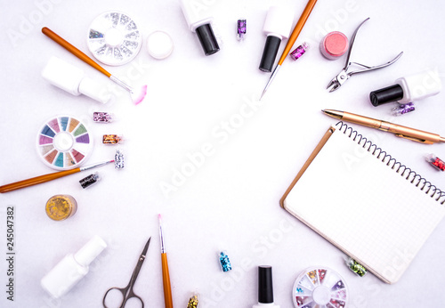 A set of cosmetic tools for manicure and pedicure on a weyt background. Gel polishes, nail files and clippers, and the lamp top view. Composition for card with a place for text