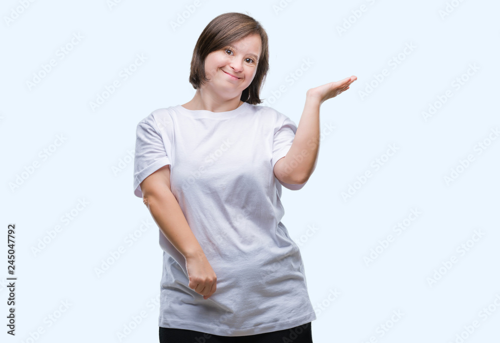 Young adult woman with down syndrome over isolated background smiling cheerful presenting and pointing with palm of hand looking at the camera. Young adult woman with down syndrome over isolated background smiling cheerful presenting and pointing with palm of hand looking at the camera.