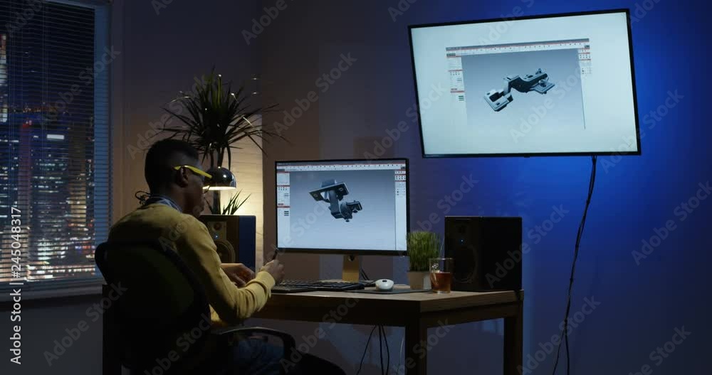 Medium shot of a young man sitting back and develops the design of 3D models of furniture accessories Medium shot of a young man sitting back and develops the design of 3D models of furniture accessories