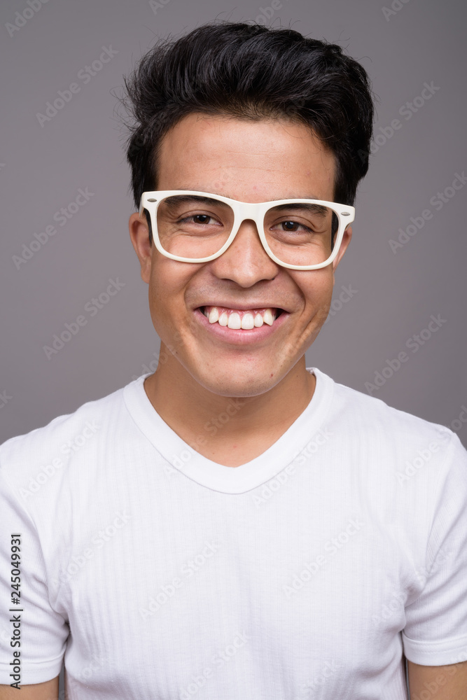 Portrait of young Asian man against gray background Portrait of young Asian man against gray background