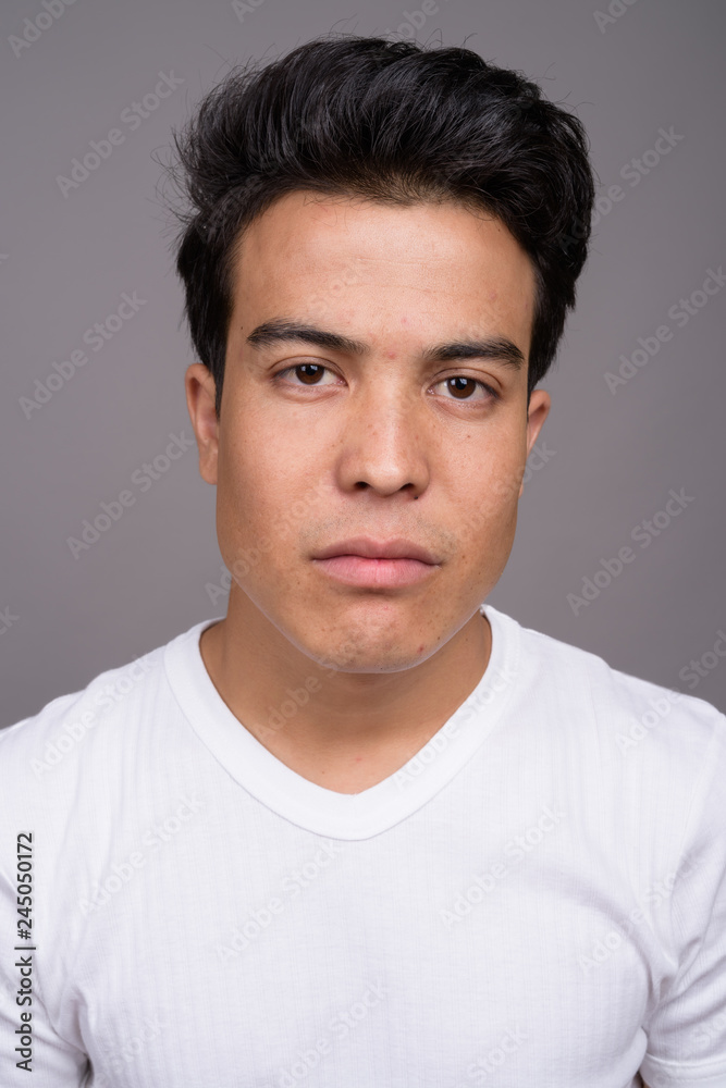 Portrait of young Asian man against gray background Portrait of young Asian man against gray background