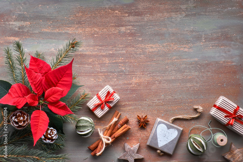 Flat lay with fir twigs, poincettia and Xmas decorations on textured background with copy-space photo