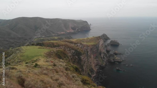 Low altitude shot off Oki island cliff edge to view wide shot aerial above coastal terrain & ocean waves. photo