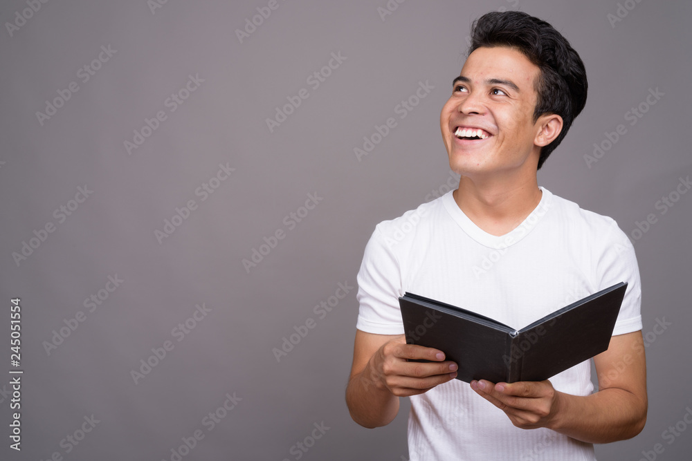 Portrait of young Asian man against gray background Portrait of young Asian man against gray background