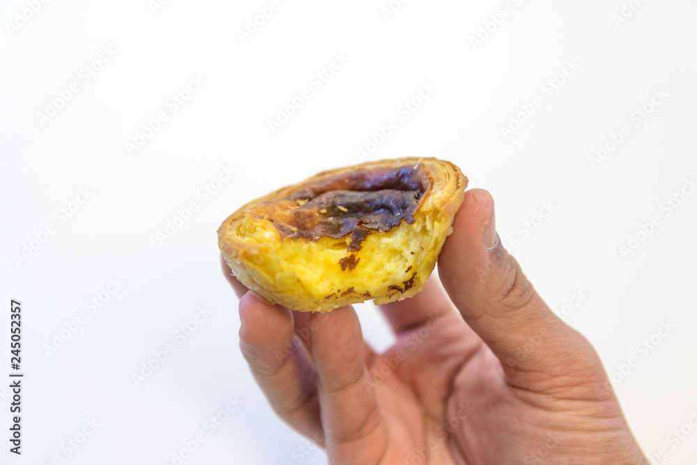 Hand holding bit egg tart isolated on white background,Traditional Portuguese sweet dessert with egg tart and custard cream. Hand holding bit egg tart isolated on white background,Traditional Portuguese sweet dessert with egg tart and custard cream.