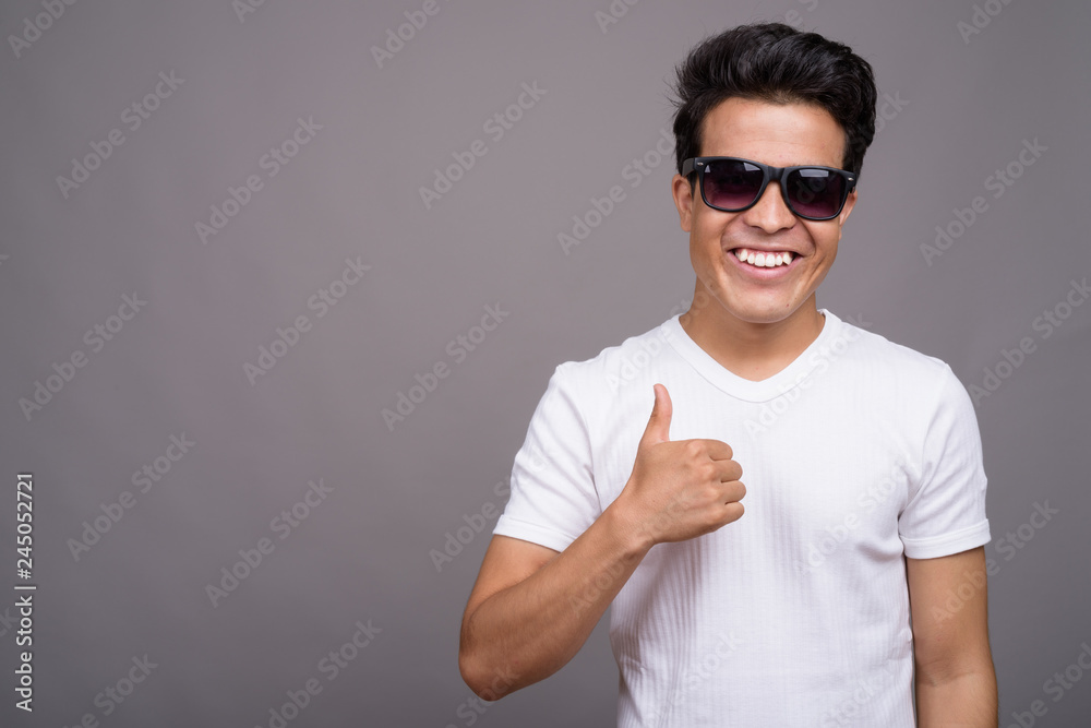 Portrait of young Asian man against gray background Portrait of young Asian man against gray background