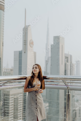 Young beauty girl having a drink at balcony with Dubai city view © F8  \ Suport Ukraine