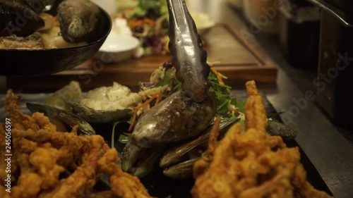 SLOWMO - Chef finishing dish New Zealand Greenshell mussells on plate with green salad, oysters and gravy - CLOSE UP photo