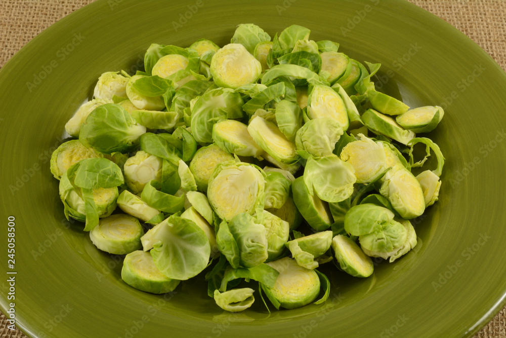 Sliced fresh raw brussel sprouts on green plate as preparation of ingredient before cooking Sliced fresh raw brussel sprouts on green plate as preparation of ingredient before cooking