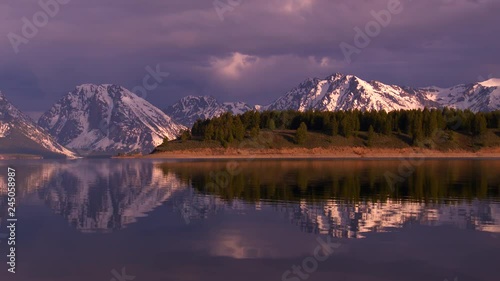 Grand Teton National Park - snow-capped mountain peaks at sunrise with dramatic lighting and cloud formations. Reflections in water. photo
