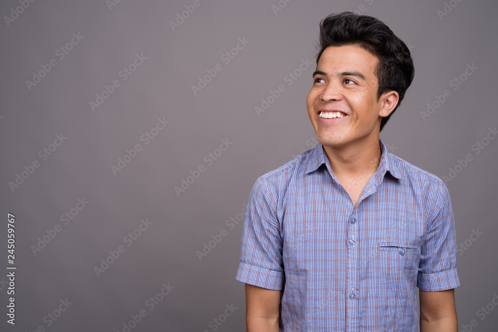 Portrait of young Asian businessman against gray background Portrait of young Asian businessman against gray background