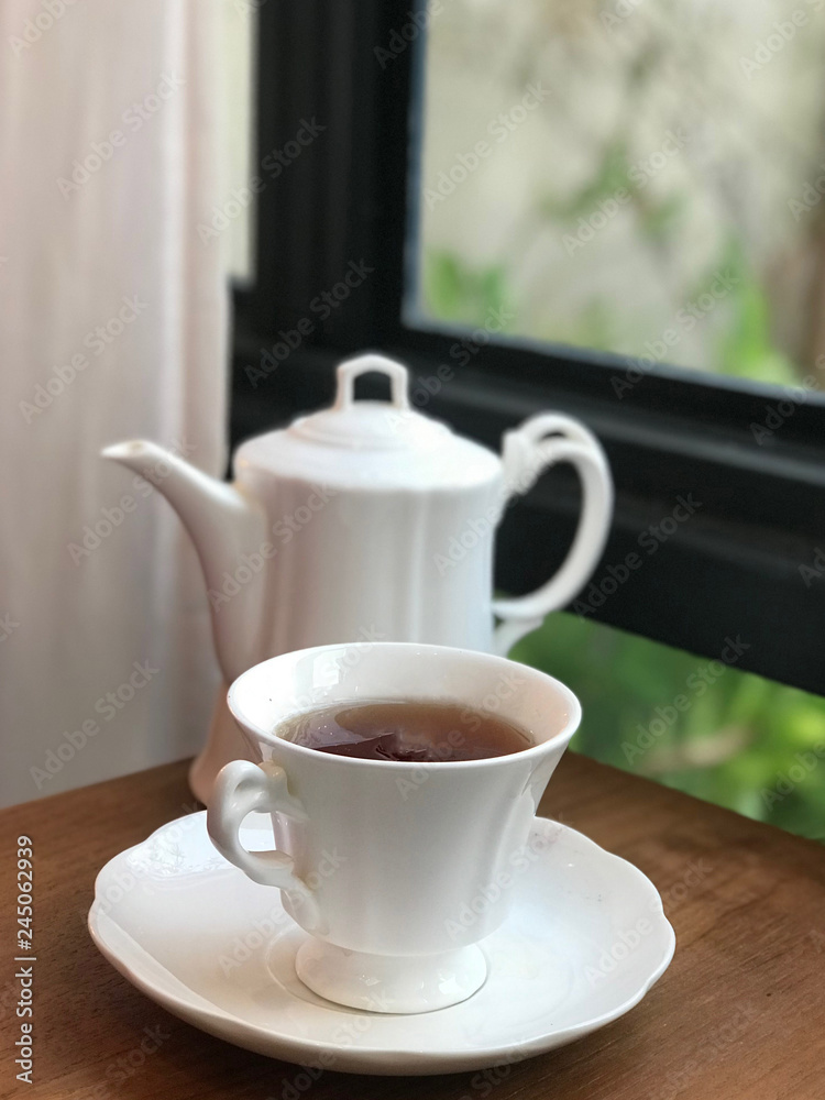White coffee cup and teapot on wooden table White coffee cup and teapot on wooden table
