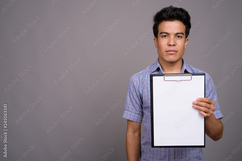 Portrait of young Asian businessman against gray background Portrait of young Asian businessman against gray background
