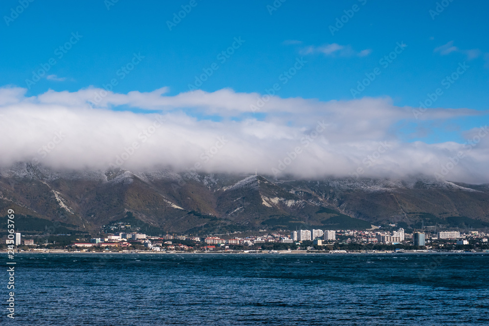 Low lying clouds on mountains and sea on foreground, resort coastline