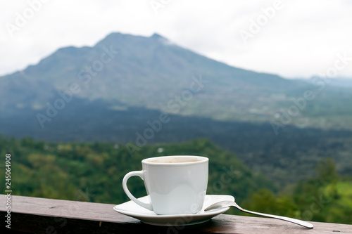 White cup of hot coffee on nature background. Bali island. Volcano Batur.