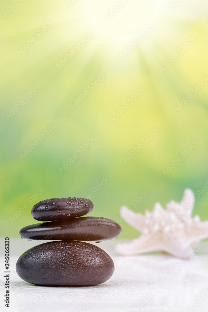 Fototapeta premium Balanced zen stones with drops of water on a green bokeh background