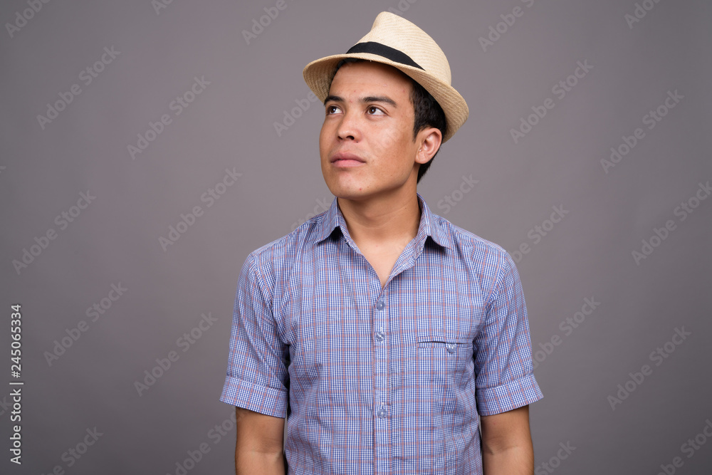 Young Asian tourist man ready for vacation against gray backgrou