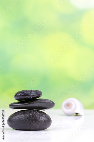 Fototapeta Naklejka Na Ścianę i Meble -  Balanced zen stones with drops of water on a green bokeh background