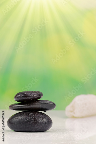 Balanced zen stones with drops of water on a green bokeh background