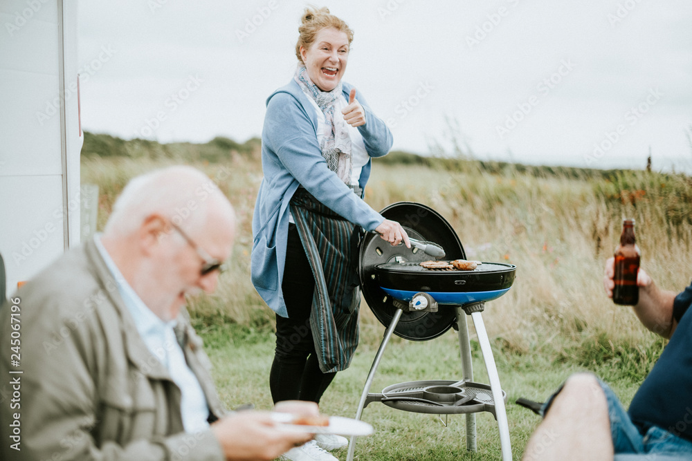 Elderly woman grilling delicious meat Elderly woman grilling delicious meat