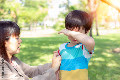 Handsome son is crying and his mom or mother is comforting him. Cute little boy miss his father, ask mom about father and lovely kid gets hungry also. He standing at park with his single mom, sunlight