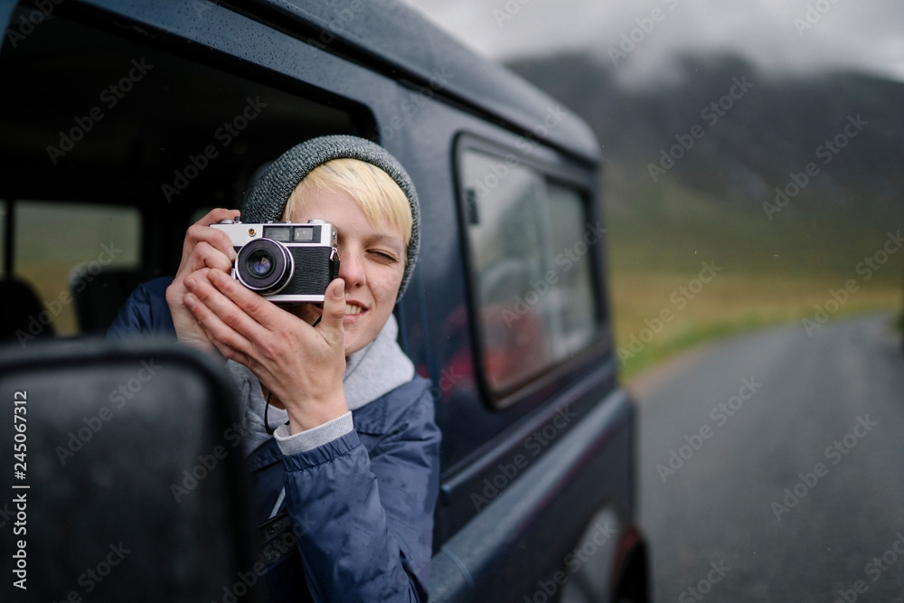 Woman taking a photo out of the car window Woman taking a photo out of the car window