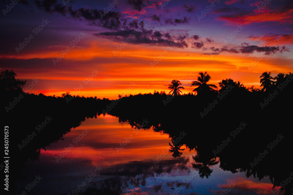 colorful sunset with clouds light rays over the river with reflections on silhouette nature landscape background  - obrazy, fototapety, plakaty 