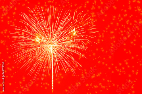 Gold fireworks celebration on red background.