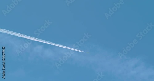 Commercial passenger jet airplane flying overhead in blue sky and leaving nice contrail. 4K photo