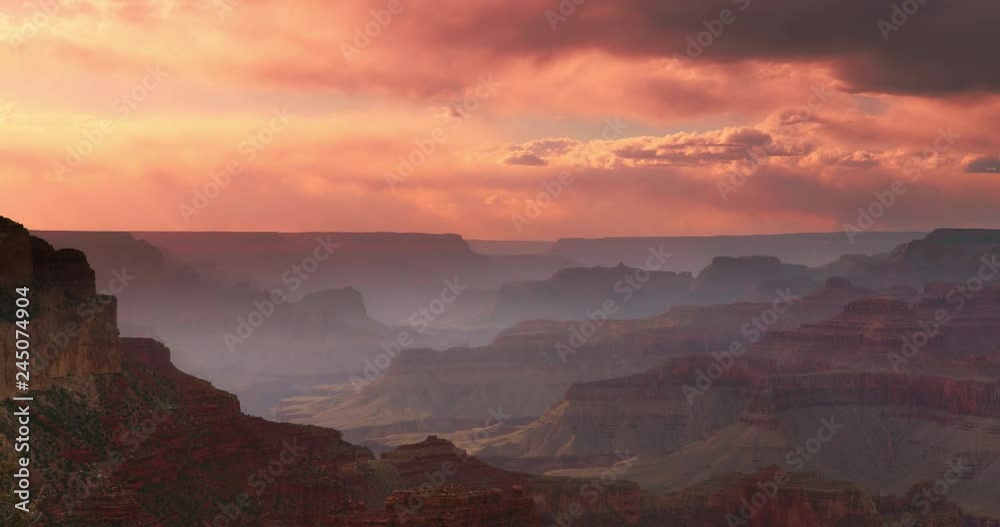 Dramatic shot of Grand Canyon at sunset with amazing lighting, clouds, red cliffs and blue skies in 4K DCI.