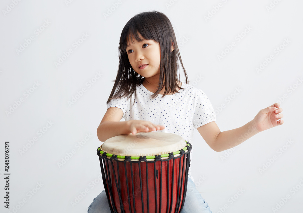 Cute Asian girl playing African drums. On white background Cute Asian girl playing African drums. On white background