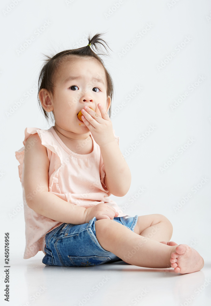 Asian little girl eating fruit, in white background Asian little girl eating fruit, in white background
