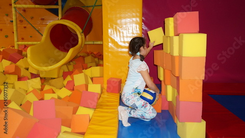 A little girl builds a wall of soft cubes on the children's playground