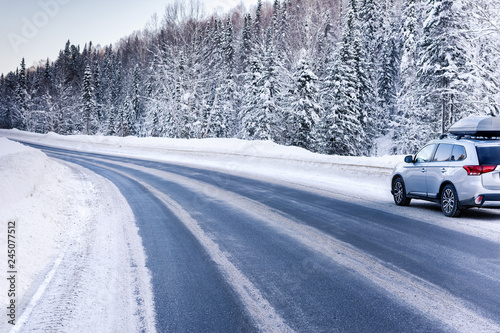 Suv car with rooftop cargo carrier trunk stay on roadside of winter road. Family trip to ski resort. Winter holidays adventure. car on winter road
