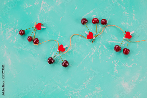 Red berry cherries and small pin hearts ,SUMMER, Still life on azure background. Flat lay, Top view. Copy space Concept - love of cherry and summer harvest.Love concept and healthy eating.Copy space