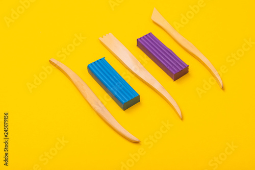 two Bars of plasticine and cutters are isolated on a yellow background