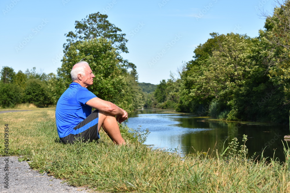Athletic Male Senior Sitting Sitting By River Athletic Male Senior Sitting Sitting By River