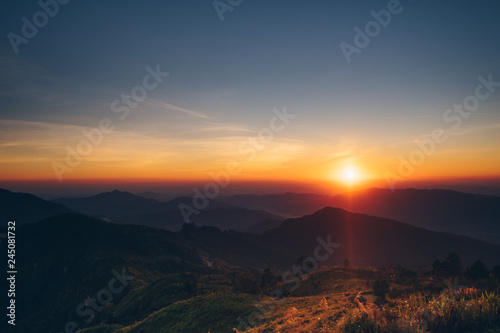 Dramatic sunset and sunrise with sun flare over mountain valley morning twilight evening sky.