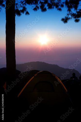 Silhouette of camping tent on the mountain at sunrise.