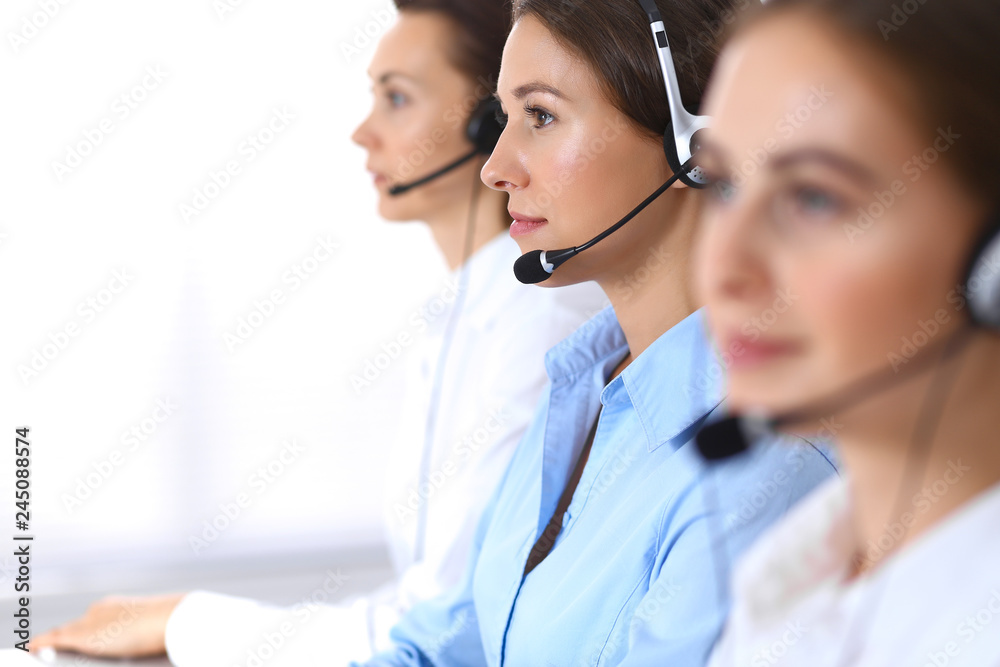 Call center. Group of operators at work. Focus at beautiful business woman in headset Call center. Group of operators at work. Focus at beautiful business woman in headset