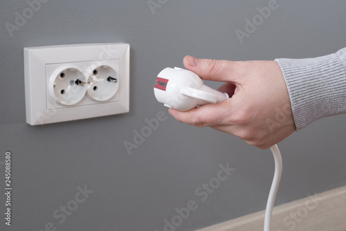 Hand inserting electrical plug into outlet