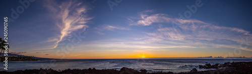 Scenic stitched panorama of a sunset with a dramatic sky over Pacific ocean  Big Island  Hawaii. Orange  yellow and red color over the horizon with a beautiful clouds in a blue sky.
