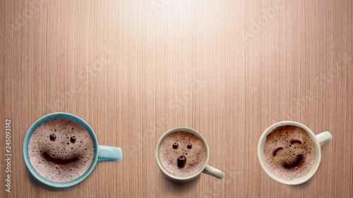 Three different faces coffee cup on a wooden table.