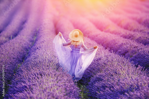 Woman in lavender flowers field at sunset in purple dress. France, Provence