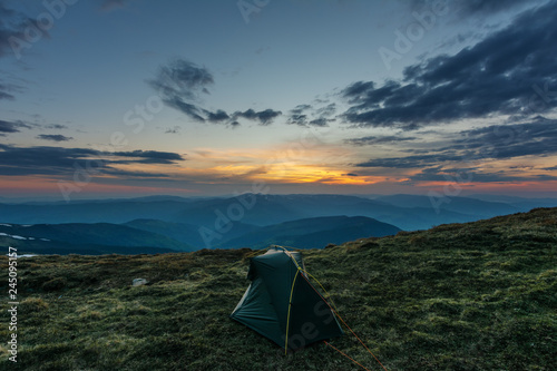 Landscape of the sunset in the Ukrainian Carpathian Mountains with a tourist and a tent.